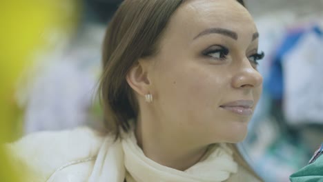 smiling woman looks at blurry children clothing close view