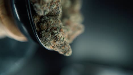 A-vertical-macro-smooth-detailed-pan-right-shot-of-a-cannabis-plant,-hybrid-orange-strains,-sativa-,marijuana-flower,-on-a-rotating-stand,-Full-HD,-super-slow-motion,-120-fps,-studio-lighting