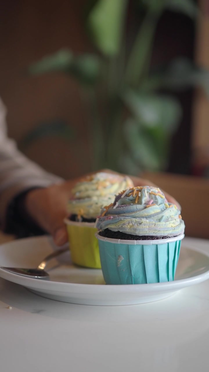 Mano che si allunga verso un cupcake colorato glassato con zuccherini colorati.