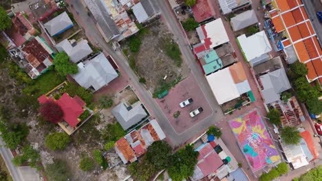 aerial top down pan over old caribbean neighborhood as cloud shadow passes on top of rusting corrugated metal roofs