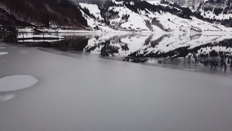 close flight over ice and water past a raft on a mountain lake in switzerland