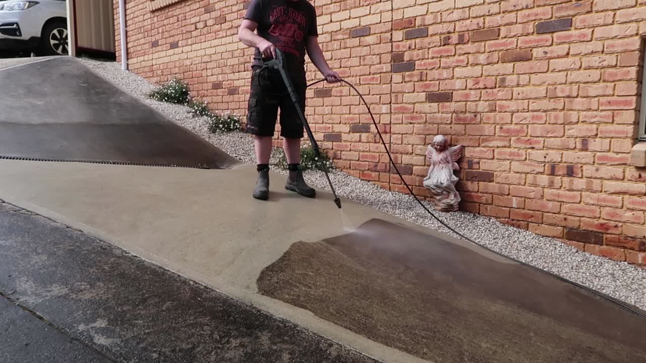 Man wearing boot power washing concrete
