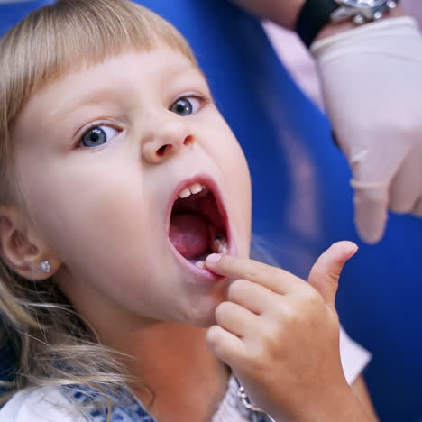 Little child in stomatology chair points at the ill tooth with a finger - close up video. Healthy teeth concept video.