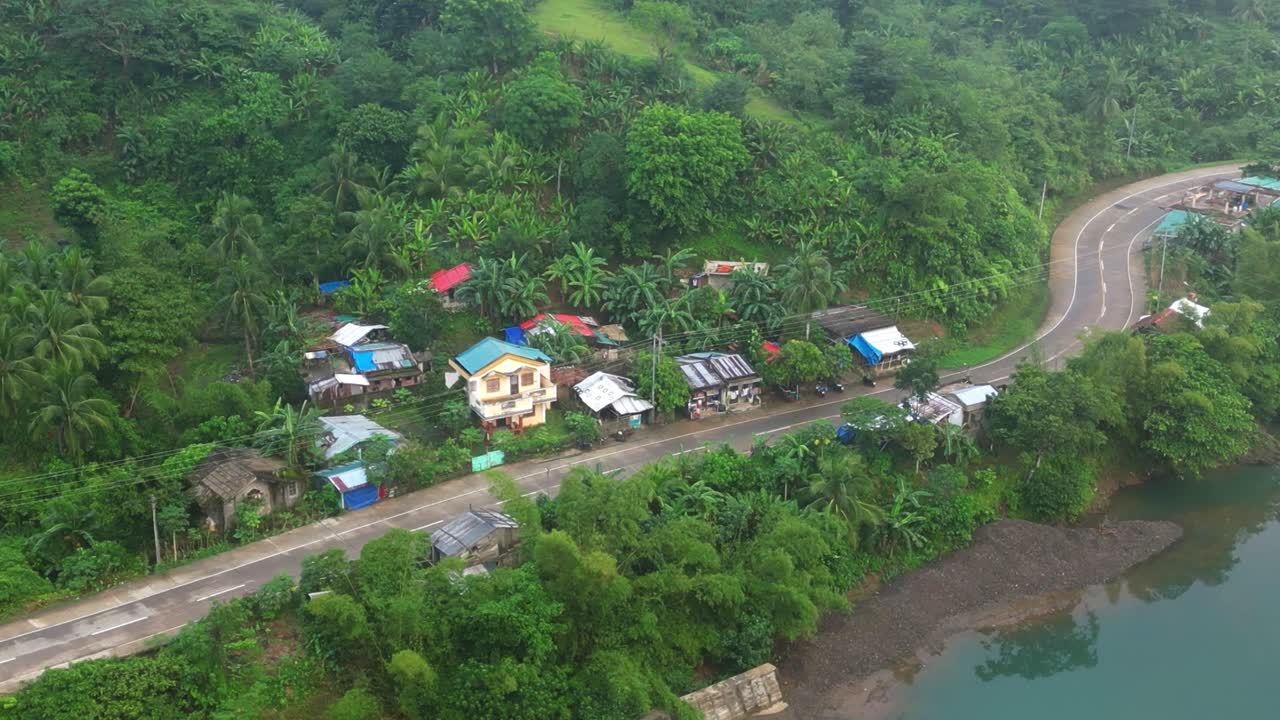 pequeño pueblo junto a la carretera en la ladera de la montaña con un río que fluye cerca del campo en catanduanes, filipinas