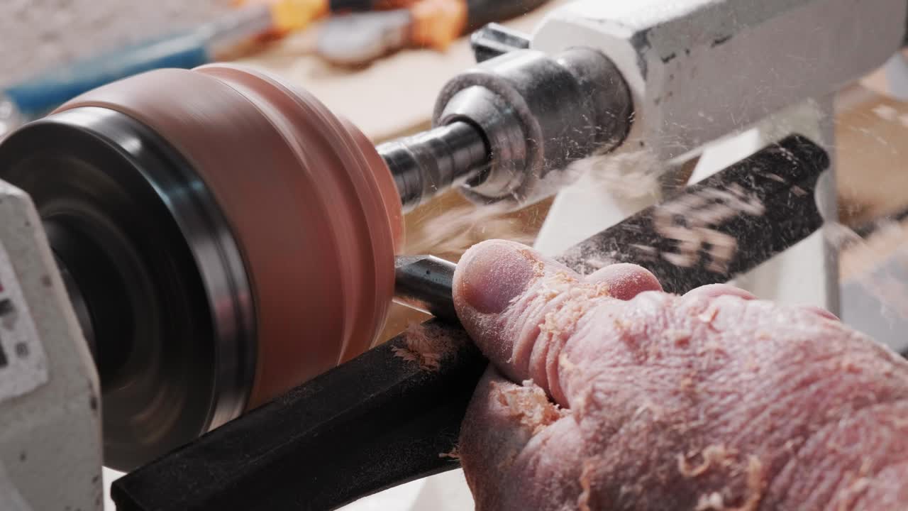 Carpenter turns a disk of wood on a lathe using a chisel