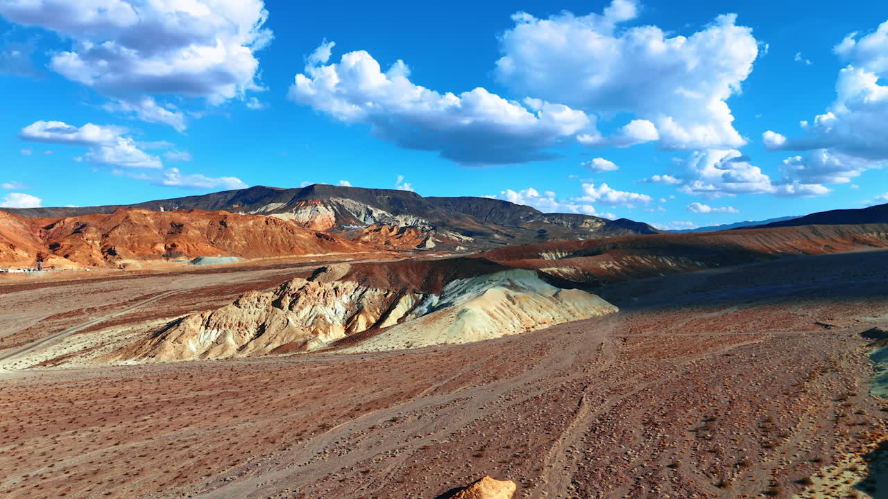 Light and dark brown bare rocks in the desert. Clouds shade the mountains in the Death Valley National Park, California, USA. Fluffy clouds hang over the landscape. Aerial perspective