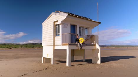 la torre de socorristas blanca y el jugador de pandereta coexisten armoniosamente en la belleza atemporal de la playa