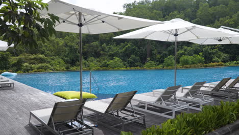 sunbeds with parasols on the poolside at renaissance bali uluwatu resort and spa in bali, indonesia