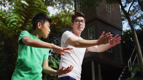 Feliz-Padre-Asiático-Haciendo-Ejercicio-En-El-Jardín-Con-Sonr,-Practicando-Tai-Chi-Juntos