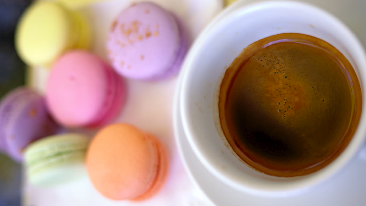 Colored french macarons with a cup of black cofee