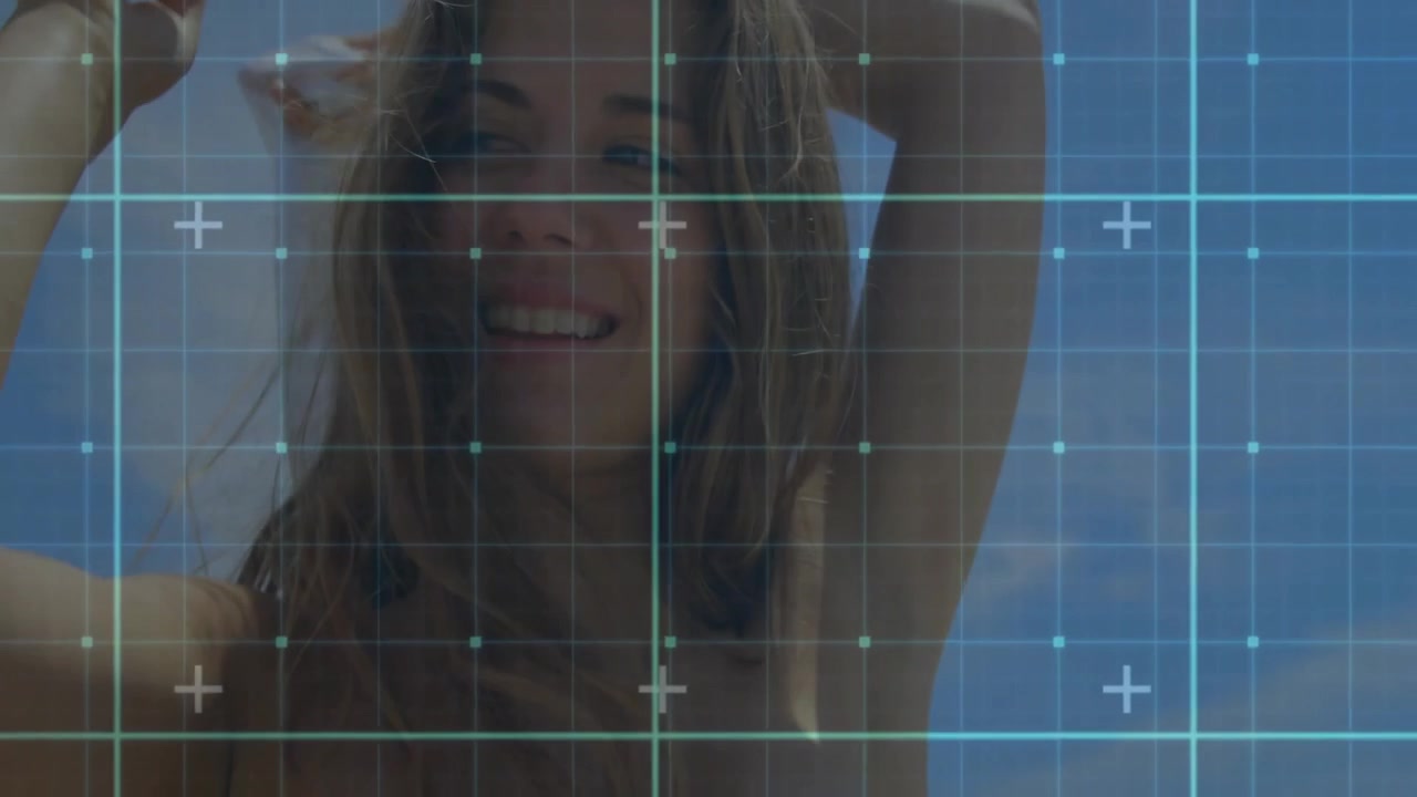 Mulher levantando toalha sob céu claro, usando tecnologia com sobreposição de grade e marcadores de adição.