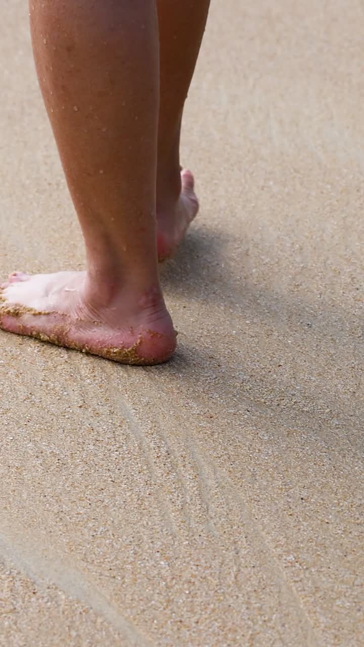 los pies caminando sobre la arena, las olas se acercan suavemente
