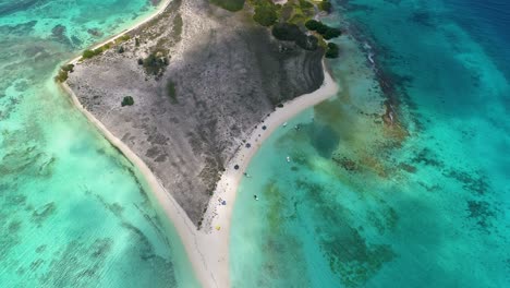 zenith-tilt-down-reveal-cayo-de-agua-tropical-island-surrounded-shades-of-blues