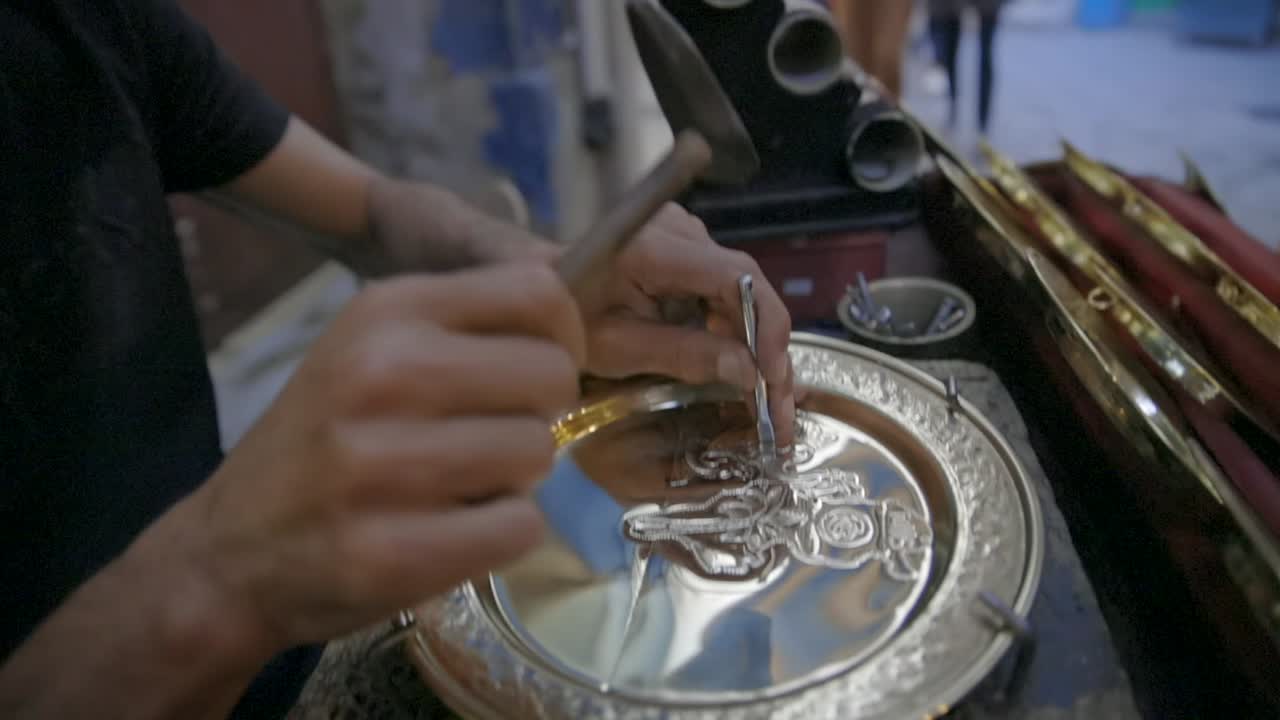 un artesano grabando hermosos motivos florales en placas de acero en las calles de túnez