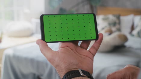 persona que sostiene un teléfono inteligente con pantalla verde