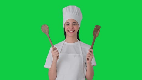 feliz india mujer chef profesional con cuchara y espátula pantalla verde