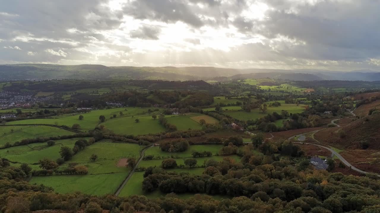 Raggi di sole che si muovono attraverso la campagna agricola inglese all'alba precoce, veduta aerea in discesa