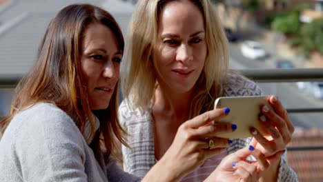 lesbian couple using mobile phone in balcony 4k