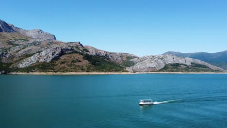 4k-Filmischer-Drohnenclip,-Der-Sich-Rückwärts-über-Den-Riaño-See-In-Castilla-Y-Leon,-Spanien-Bewegt,-Mit-Einem-Boot,-Das-Sich-Durch-Das-Wasser-Bewegt