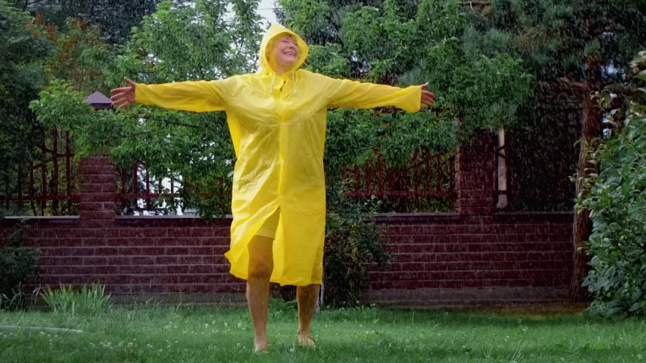 Woman enjoying a rain shower in a yellow raincoat