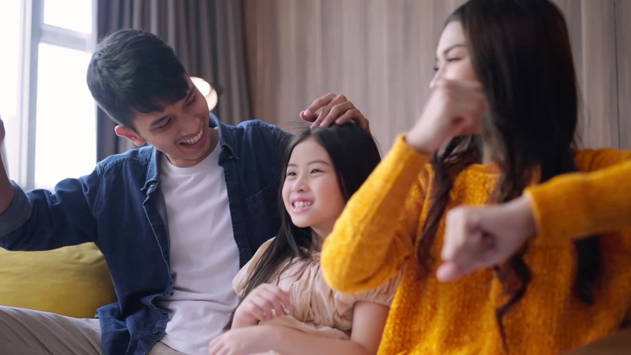 재미있고 즐거운 출발 순간 아시아 가족 부모와 딸은 함께 온라인 스트리밍 콘서트를보고 소파 소파에 함께 집에서 거실에서 행복 가족 춤 움직이는 손 기쁜