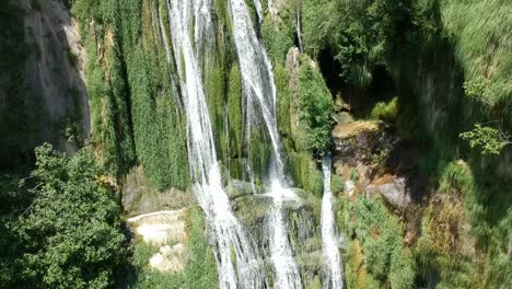 Aerial-views-of-a-waterfall-with-a-cave-and-an-old-building-in-Catalonia,-Spain