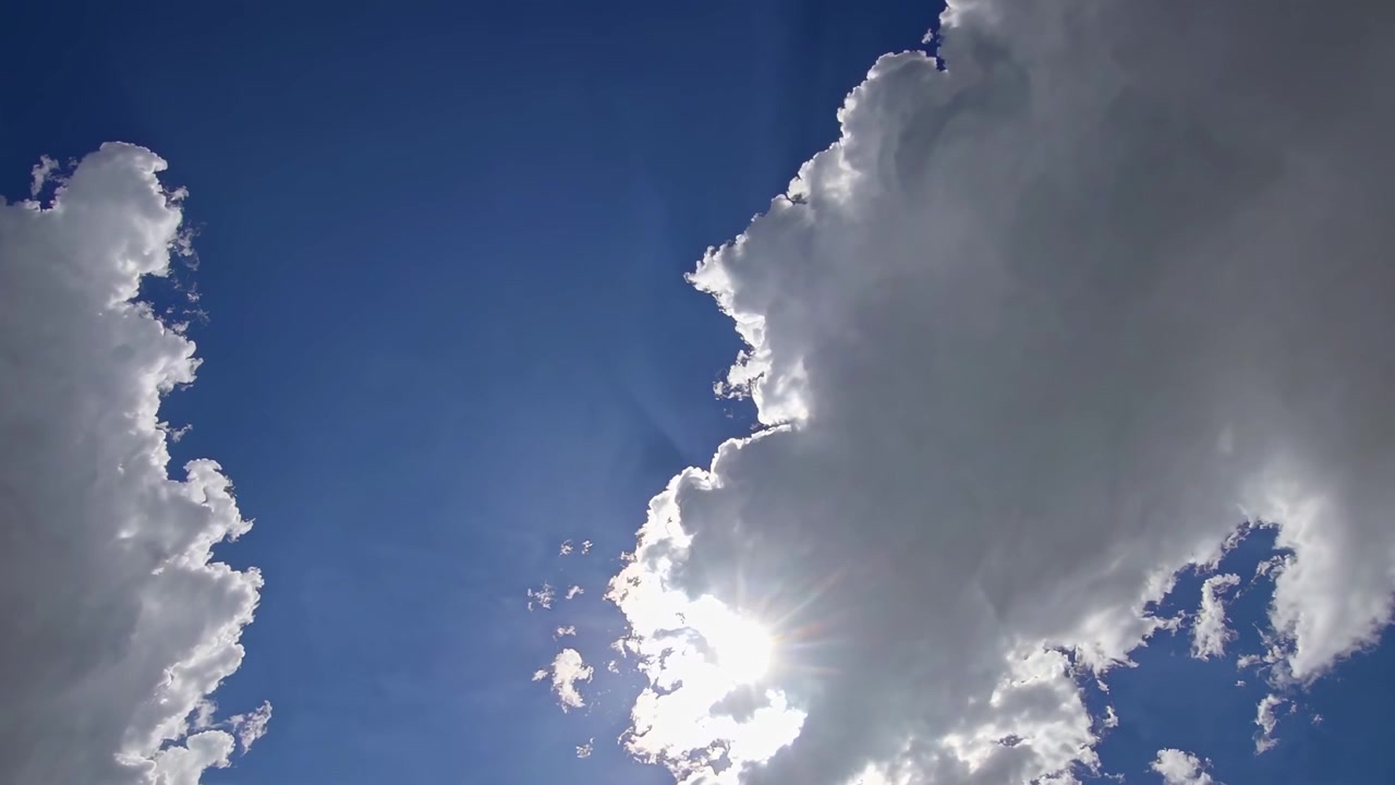 Luz solar espreitando por entre nuvens brancas fofas no céu azul
