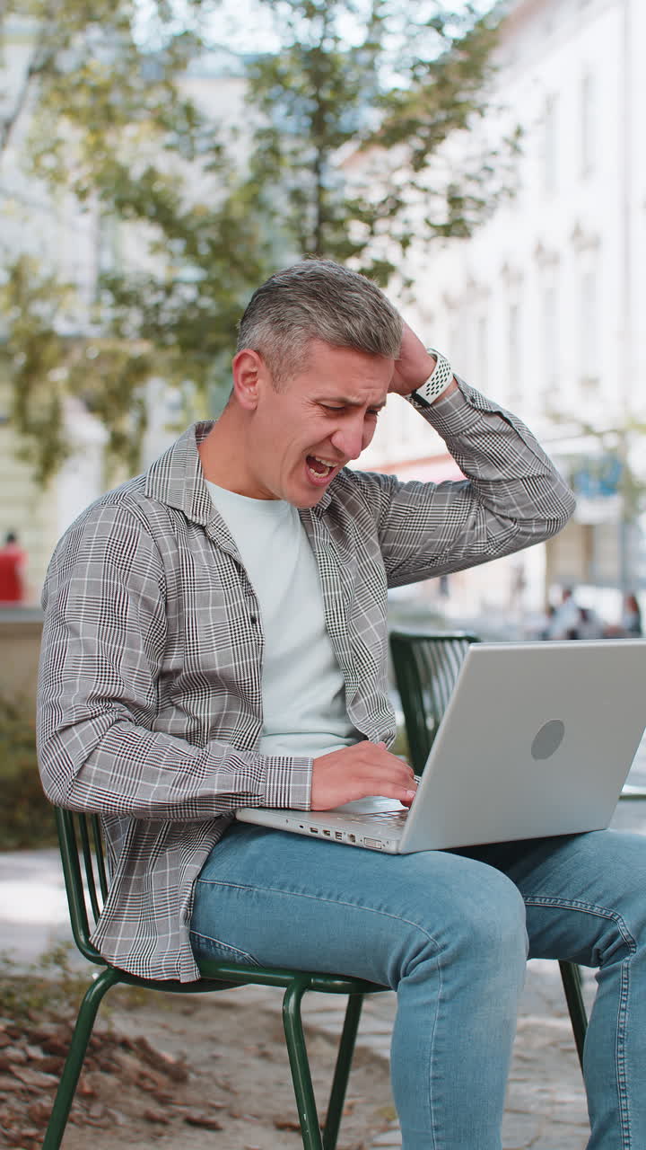 un hombre maduro que usa una computadora portátil pierde siendo sorprendido por los resultados repentinos de la lotería pérdida falla en la calle de la ciudad