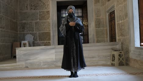 mujer con hijab orando en una mezquita histórica