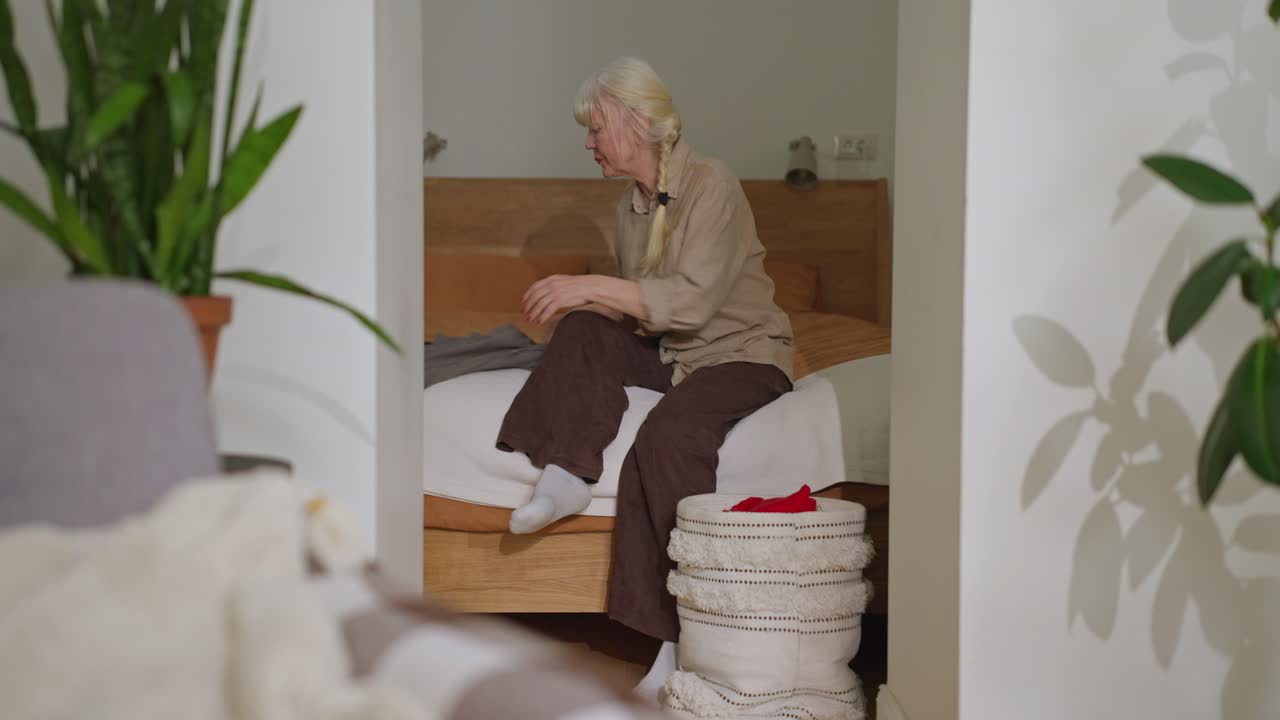 Elderly Woman Folding Clothes in Bedroom