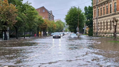 cars driving on a flooded city street after heavy rain