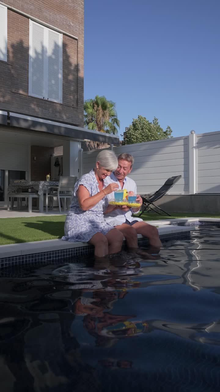 Coppia di anziani si gode un drink a bordo piscina