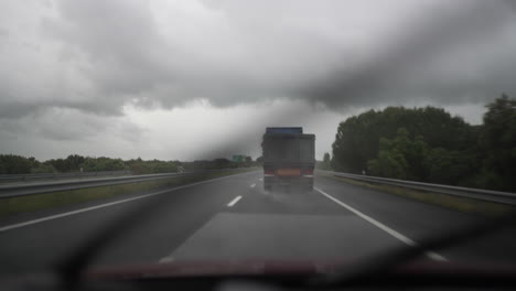 truck driving on a highway under cloudy skies with rain and blurred road perspective