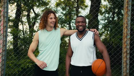 Portrait-of-two-teammates-posing-and-looking-at-the-camera-and-smiling-against-the-background-of-a-mesh-fence-on-a-bucksball-court.-Preparation-for-the-game