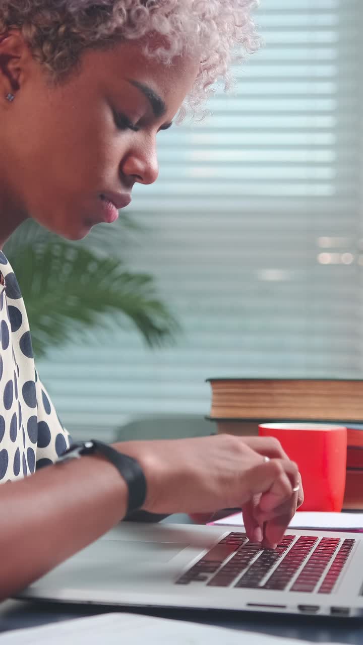 Woman typing on laptop at a modern workspace with books