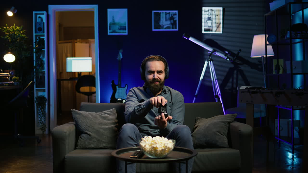 집에서 컨트롤러와 함께 게임을 하는 남자가 패배한 후 화를 내고 있습니다.