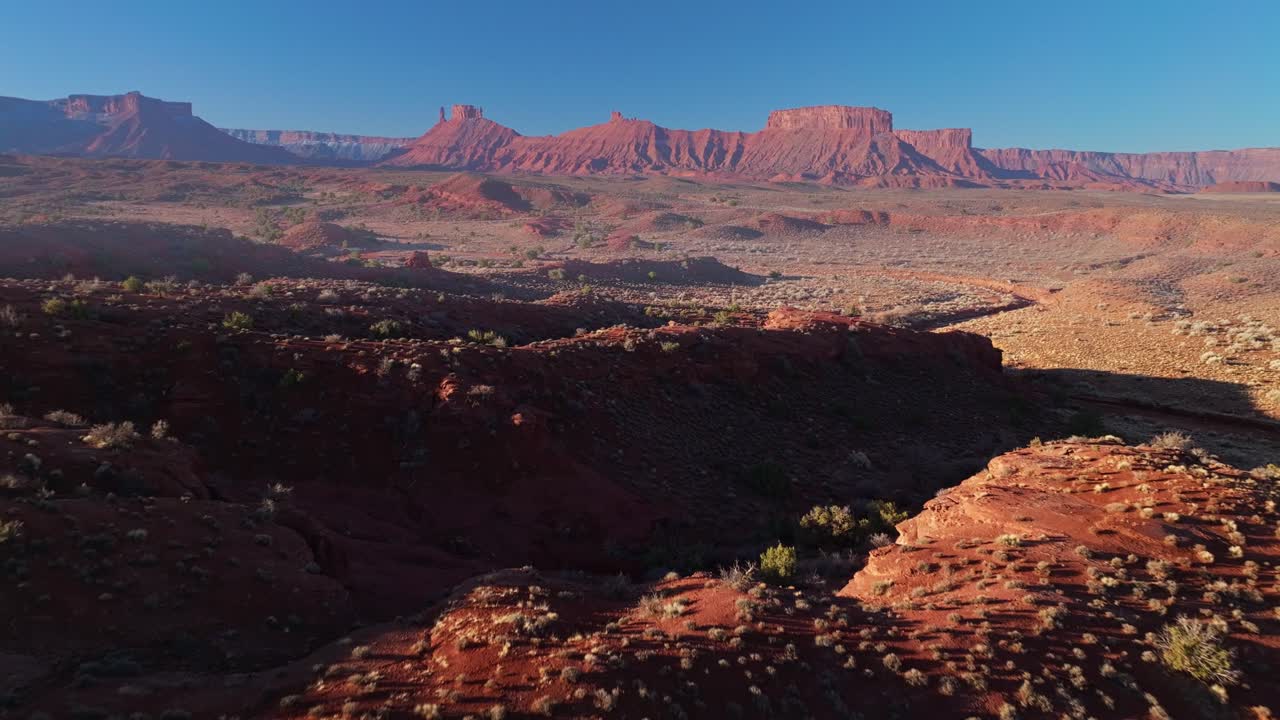 Aerial dolly establishing of Moab dramatic rock formations with sharp cliffs and winding valley floors below washes