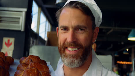 smiling chef holding ray of baked buns 4k