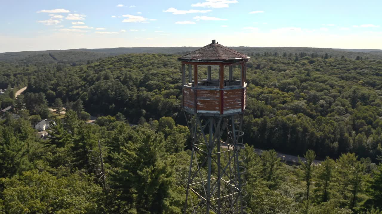 Rotating shot around fire lookout tower beside lake in rural Ontario cottage country