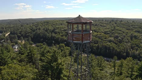 rotating shot around fire lookout tower beside lake in rural ontario cottage country