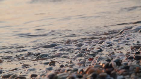 Real-time-extreme-close-up-shot-shoreline,-ocean-over-pebbles-in-Almeria,-Spain