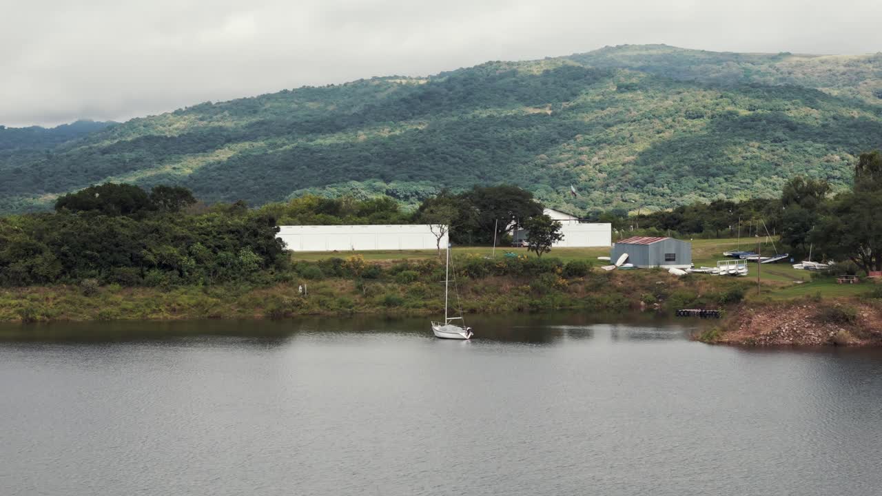 Sailboat Moored on a Lake with Mountains and Buildings in the Background