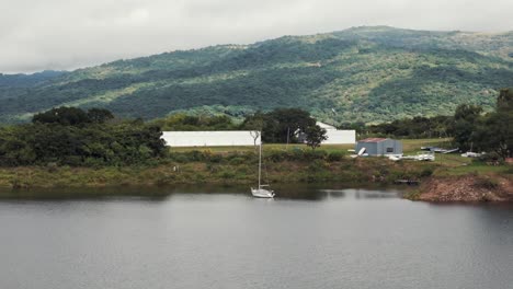 sailboat moored on a lake with mountains and buildings in the background