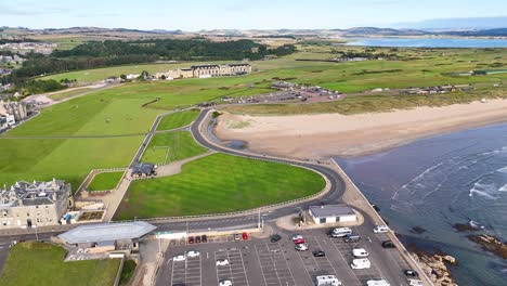 aerial drone video gliding over historic golf course, victorian buildings, and sandy coastline in scotland