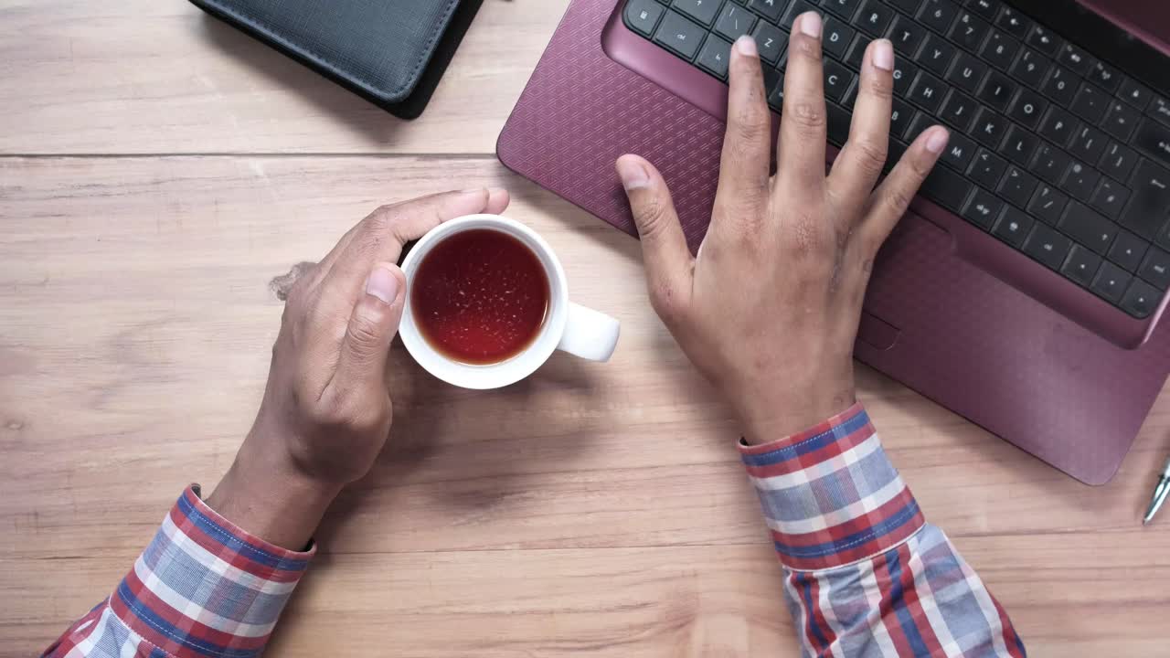 Persona che lavora a una scrivania con laptop e tè