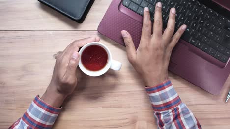 person working at a desk with laptop and tea