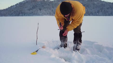 ice fishing - man fishing on the frozen lake covered with snow