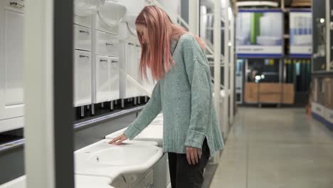 blonde woman is choosing a new ceramic sink in a store