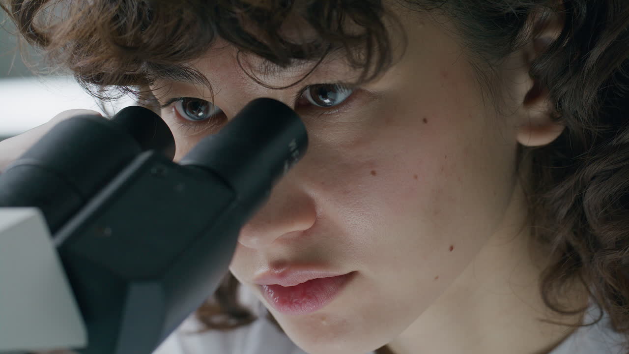 Close-Up of Concentrated Female Scientist Working with Microscope in Lab