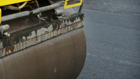 process of asphalting road construction infrastructure by compressing, compacting, leveling and smoothing the asphalt road surface using a tandem roller